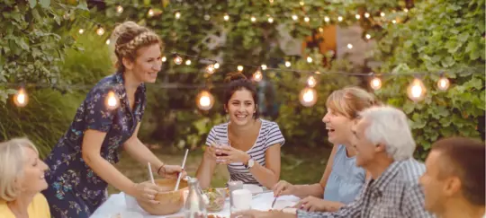 family dinner in yard with hanging lights